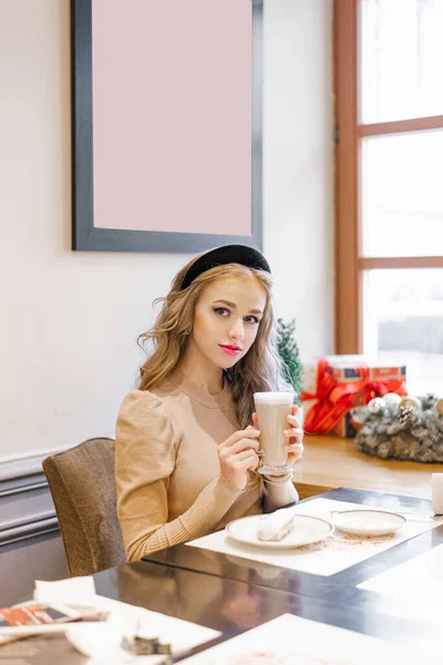Ένα Όμορφο Κορίτσι Κάθεται Ένα Ζεστό Χριστουγεννιάτικο Καφέ Ένα Φλιτζάνι — Φωτογραφία Αρχείου