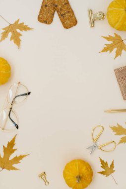 Bir blogcu ya da serbest çalışan için rahat bir ofis. Düşmüş yapraklar, balkabağı, makas, gözlükler, not defteri, kurabiyeler ve çerçeveli bej bir arka plan üzerinde bir kalem. Düz yatıyordu. Kopya alanı ile sonbahar bileşimi.