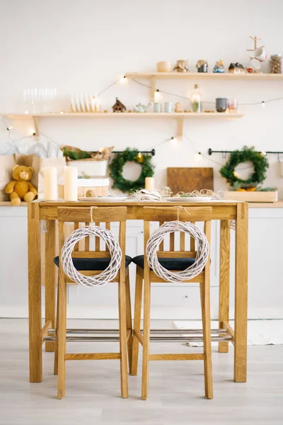 Wooden dining table with chairs decorated for Christmas and New Year in a bright Scandinavian style dining room