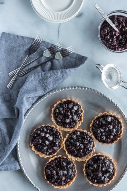 Üzerinde ekstra yaban mersini sosu olan metal servis tepsisi üzerindeki yaban mersinli turtaların en üstten görünüşü.. 