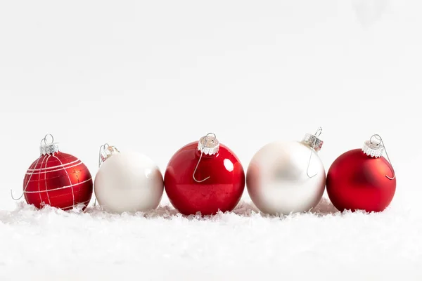 Christmas balls in a row on snow against a white background. Royalty Free Stock Images