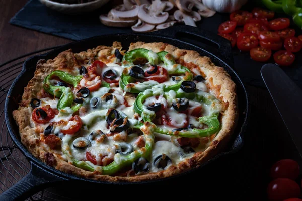 Grote luxe diepschotel pizza tegen een donkere achtergrond. — Stockfoto