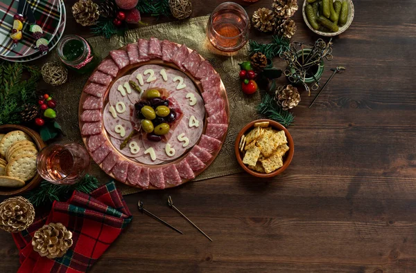 Blick von oben auf eine Charcuterie-Platte, die in eine Uhr verwandelt wurde, umgeben von festlichen Speisen und Dekorationen. — Stockfoto