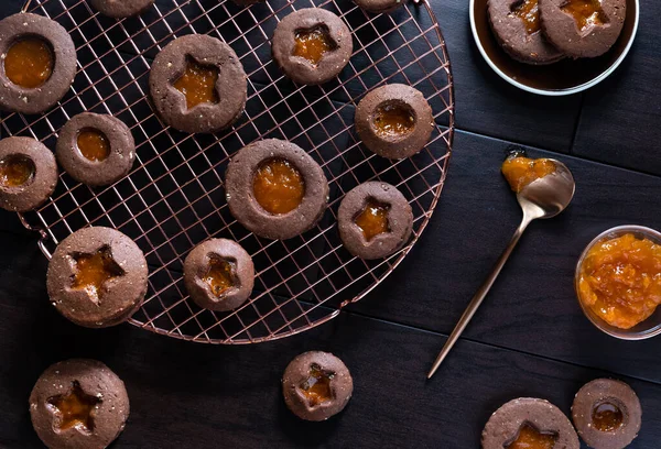 Top down view of chocolate Linzer cookies with apricot preserves on a copper cooling rack. — Stock Photo, Image