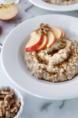 Bir kase çelik kesim yulaf ve kahverengi şekerli elma dilimleri ve ceviz yemeye hazır..