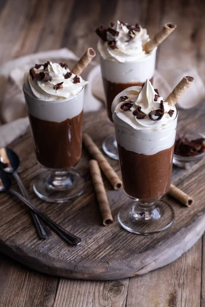 Tres parfaits de mousse de chocolate con crema batida y virutas de chocolate en una tabla de madera. — Foto de Stock