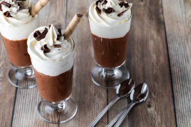 Krem şantili çikolatalı krema ve ahşap masadaki çikolata parçacıkları..