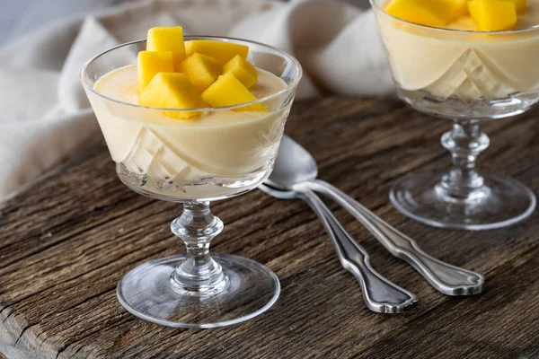 A close up of mango mousse dessert parfaits on a rustic wooden board.