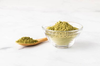 Moringa tozuyla dolu cam bir kapta aynı tozla dolu küçük bir tahta kaşık..