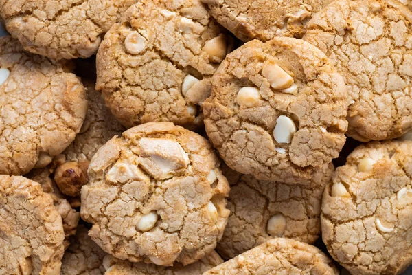 Top down macro of a pile of white chocolate chip and macadamia nut cookies.