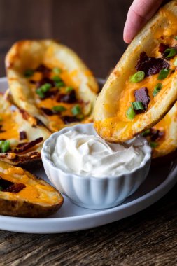 Patates kabuğunu ekşi kremaya batıran bir elin yakınına..