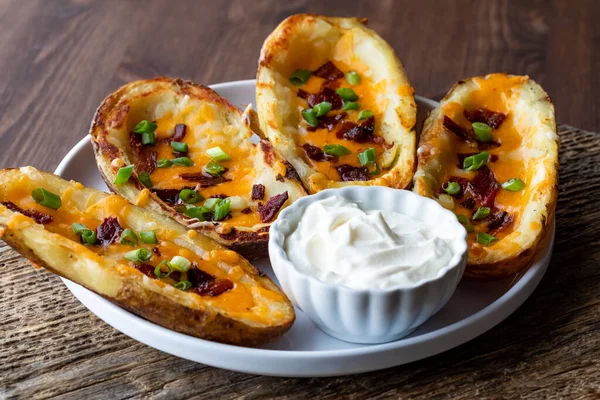 Prato de peles de batata caseiras com um pequeno prato de creme azedo para mergulhar. — Fotografia de Stock