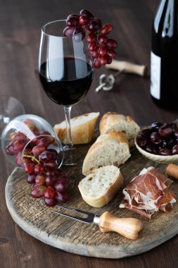 Ahşap bir masa üzerinde kırmızı şarap ve üzümlü kırsal şarküteri tahtası..