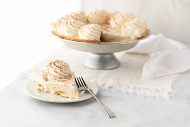 Bir parça muzlu kremalı turta, parlak bir pencereye karşı arkasında dolu bir turta..