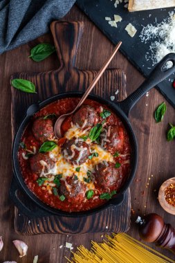 İtalyan mutfağındaki makarna malzemeleriyle çevrili soslu köftelerin yukarıdan görünüşü.