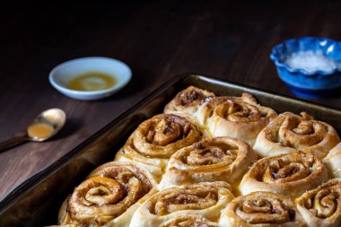 Ev yapımı tuzlu karamelli tarçınlı çöreklerle dolu bir tavayı kapat..