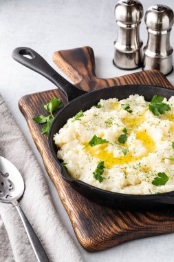 Patates püresini ahşap bir tahtanın üzerinde, arkasında tuz ve biber kabıyla dökme demir tavada kapat..
