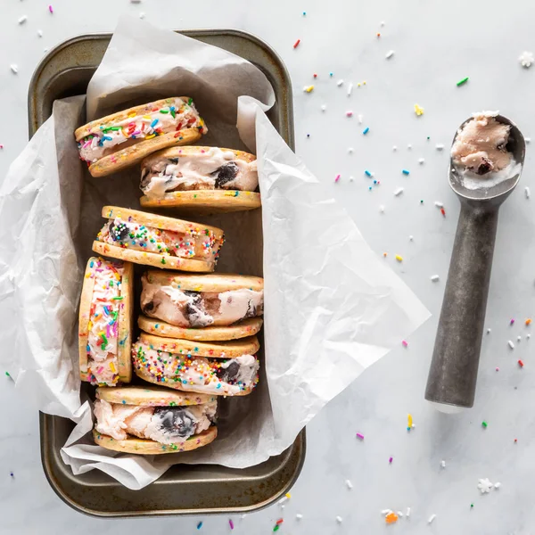 Ev yapımı dondurmalı sandviçler ve dondurma kepçesiyle dolu kağıt kaplama kağıdın yukarıdan görünüşü. — Stok fotoğraf