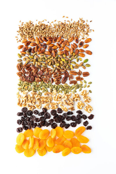 Сверху вниз вид различных орехов, семян и сухофруктов, используемых в создании след смеси на белом фоне.