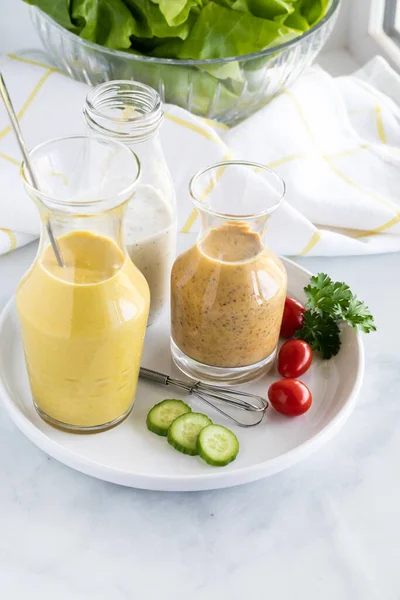 Trois vinaigrettes maison comprenant du tahini au curcuma, de la moutarde au miel et du poppyseed, prises d'en haut. — Photo