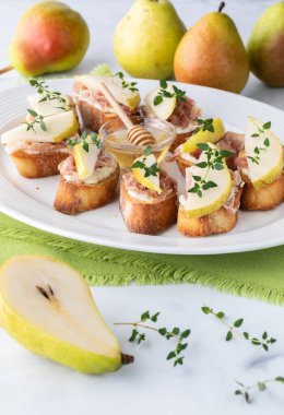 Krem peynir, armut ve prosciutto ile kaplı kabuklu crostini aperatifleri yemek için hazır..