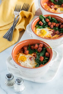 Çorba kabında yumurta sotelenmiş ıspanak ve sucuklu sosis, yemek için hazır..
