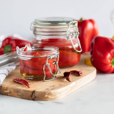 Kavanozların yakın görüntüsü kavrulmuş kırmızı biberler olgun biberler ve kurutulmuş biberlerle çevrili..