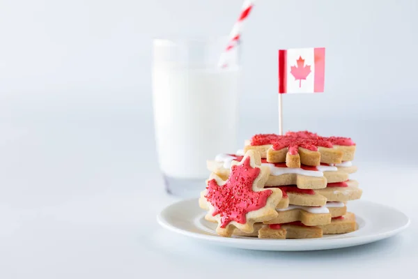 Kanada flaggt Zuckerkekse auf einem Teller mit einem Glas Milch im Rücken. — Stockfoto