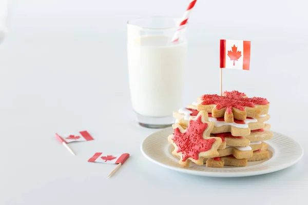 Ein Teller voller kanadischer Flaggen-Zuckerkekse mit einem Glas Milch dahinter und Platz nach links kopieren. — Stockfoto