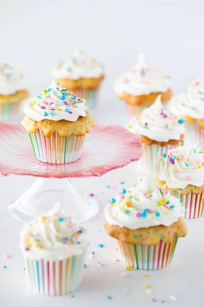 Ett piedestalstånd med en konfetti cupcake och flera muffins som omger och nedanför. — Stockfoto
