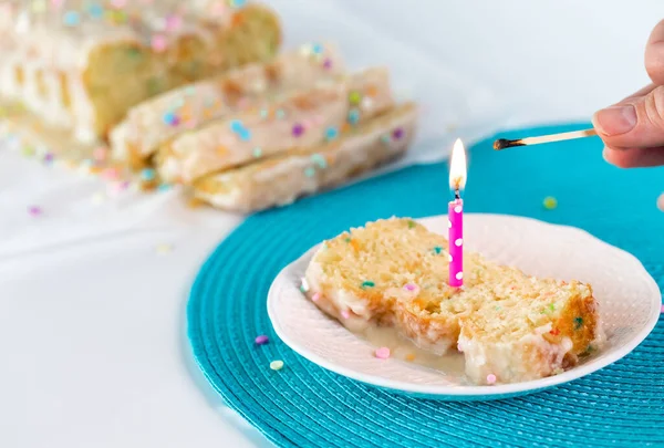 Ένα φρεσκοαναμμένο κερί πάνω σε μια φέτα κέικ με ένα χέρι που κρατάει ένα καμένο σπίρτο.. — Φωτογραφία Αρχείου
