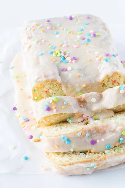 A sliced loaf of confetti cake ready for serving against a bright white background. — Stockfoto