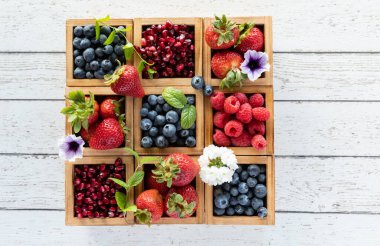 Çeşitli böğürtlenlerle dolu bir kompartıman kutusu, her iki tarafında fotokopi alanı olan ahşap bir masanın üzerinde..
