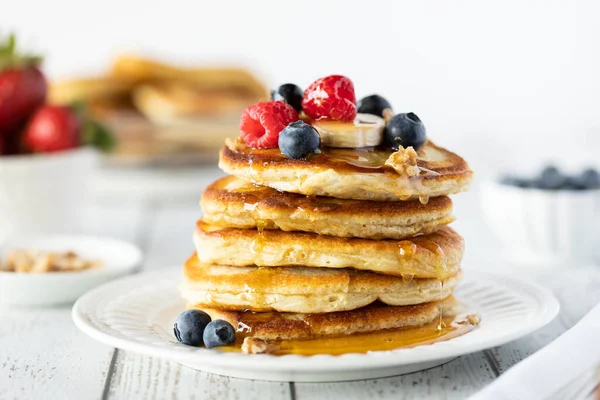 Close up of a stack of buttermilk pancakes topped with berries and syrup dripping down the sides. — Stock Photo, Image
