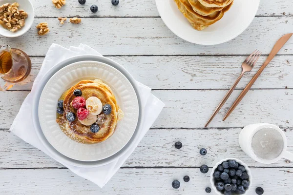 Top down view of a stack of buttermilk pancakes topped with fruit and syrup ready for eating. — Stock Photo, Image