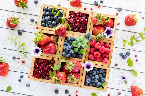 Угловой вид на деревянный ящик, заполненный различными ягодами, ягодами и травами, разбросанными по всему периметру. — стоковое фото