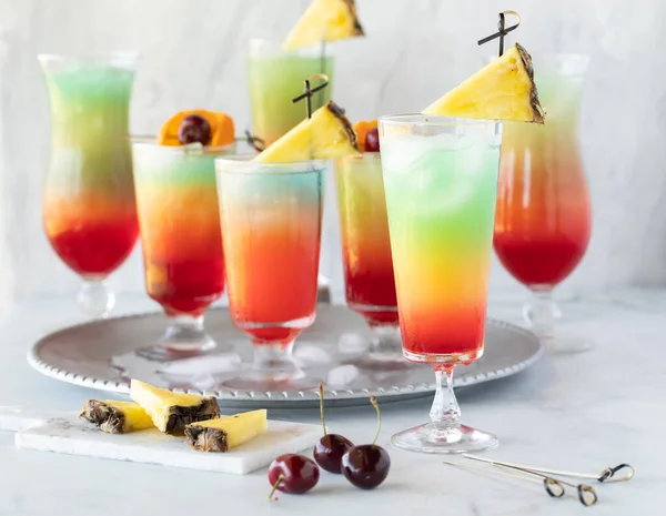 Ein Tablett mit farbenfrohen Mocktails, mit einem davor, bereit zum Trinken. — Stockfoto