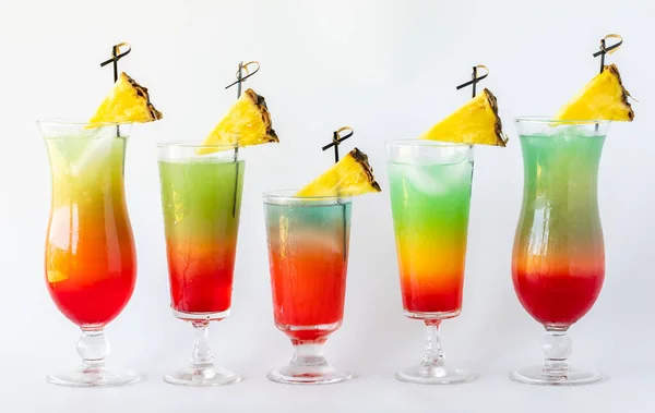 Вид спереди на ряд ярких красочных коктейлей, украшенных клиньями ананаса. — стоковое фото
