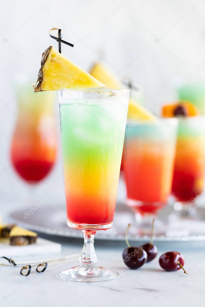 Glasses of frosty colourful mocktails surrounded by fruit for garnishment. 