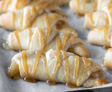 Karamel soslu taze pişmiş elmalı rulo hilal çöreklerinin yakın görüntüsü..