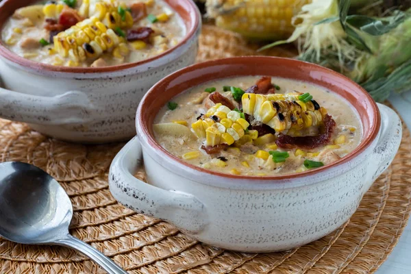 Close up view of a soup crock filled with chicken and corn chowder topped with grilled corn, ready for eating. — Stock Photo, Image