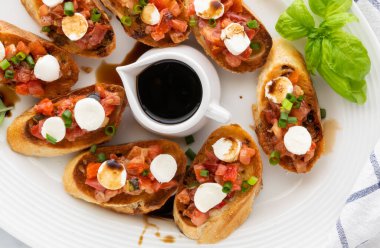 Ortasında bir tabak balzamik sirke olan bir tabak bruschetta tabağı..