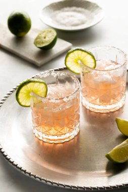 İki margarita, limon ve tuzlu jantlarla süslenmiş, içilmeye hazır..