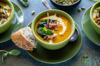 Yakından bir kase kremalı tereyağlı kabak çorbasına bak kabak tohumlu ekmek ile servis edilir.. 