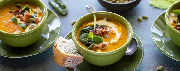 Vista estreita de tigelas de sopa de abóbora enfeitada com verduras, bacon e sementes de abóbora. — Fotografia de Stock