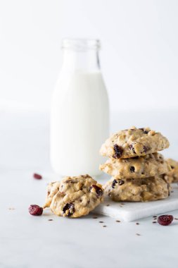 Bir yığın yaban mersini ve keten kahvaltı kurabiyesi ve arkasında bir şişe süt..