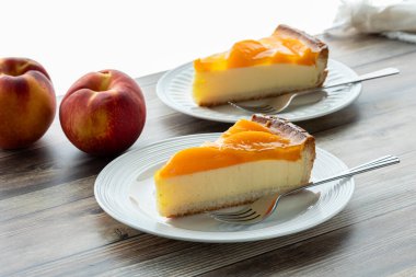 Masadaki şeftalili cheesecake dilimleri Parlak bir pencereye karşı, yemeye hazır.