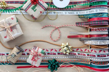 Kahverengi kağıda yayılmış bir sürü tatil kurdelesi ve paketlenmiş hediyeler..