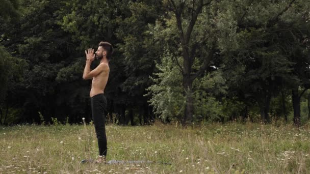 Мужчина практикует йогу снаружи — стоковое видео