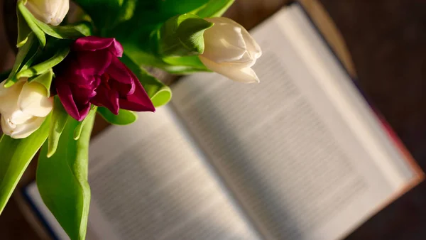 Kitabın yanındaki laleler çiçek açıyor.